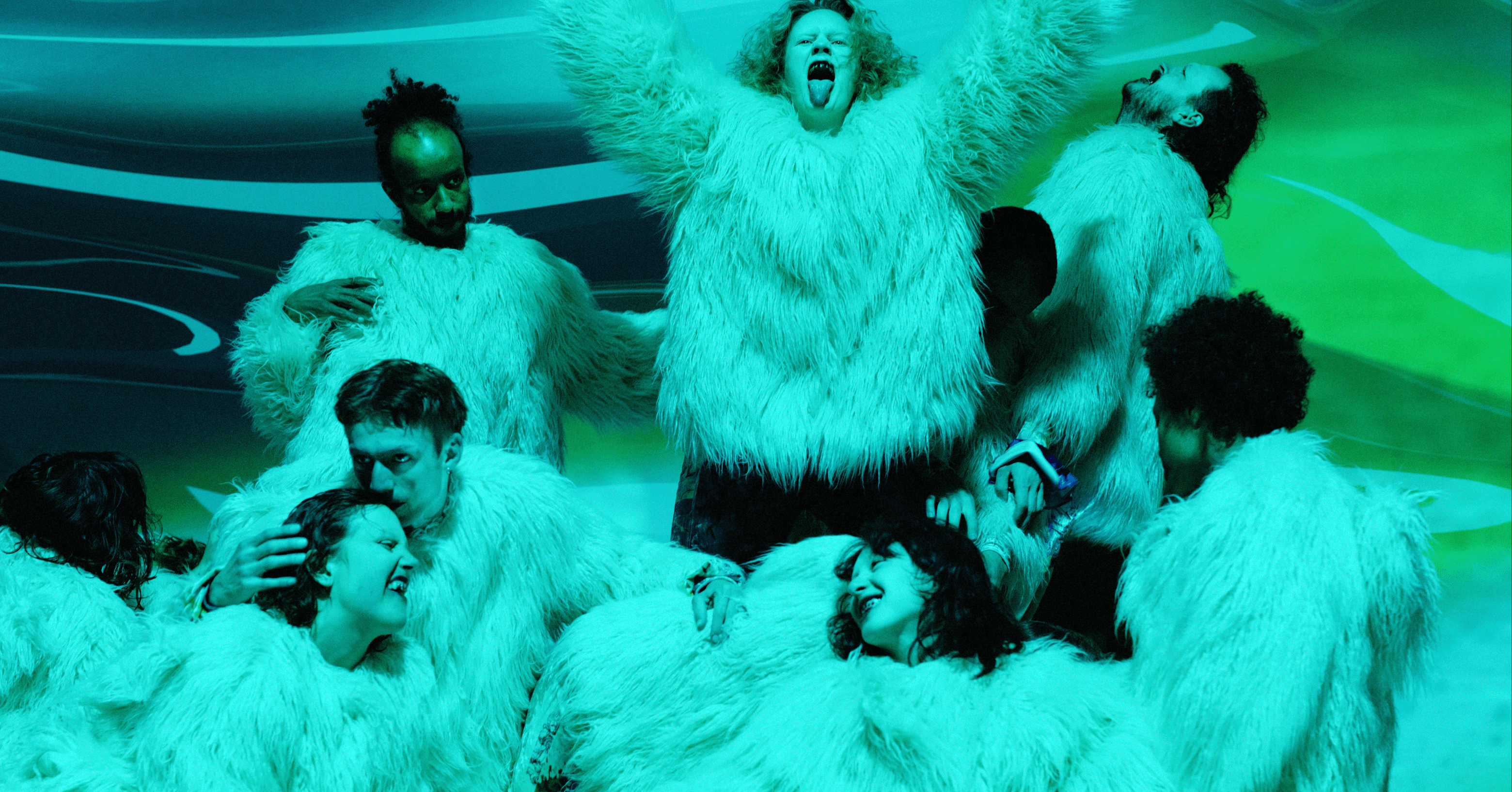 A group of people wearing fluffy white outfits, posing energetically against a green background.